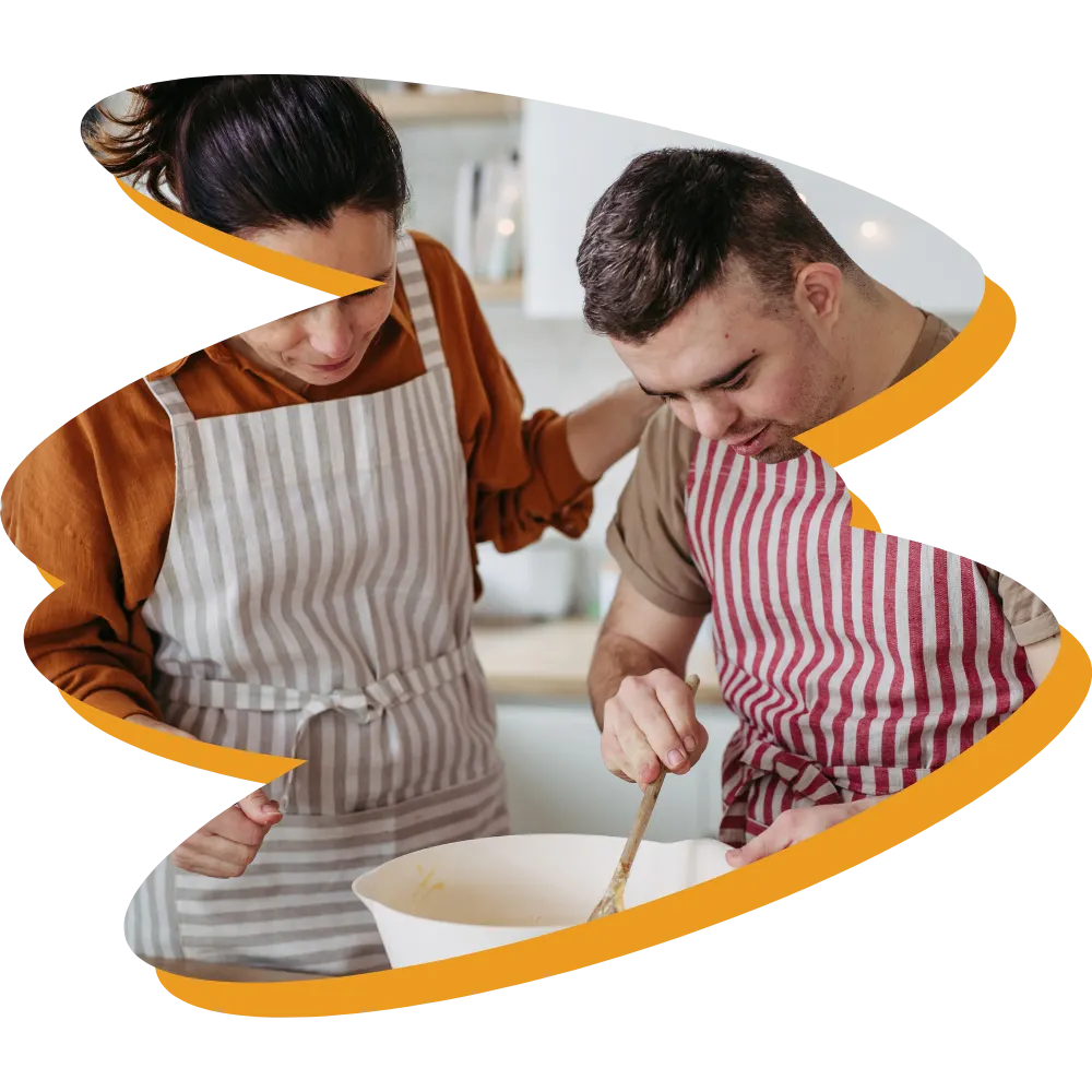 Disabled man with down syndrome cooking with support worker