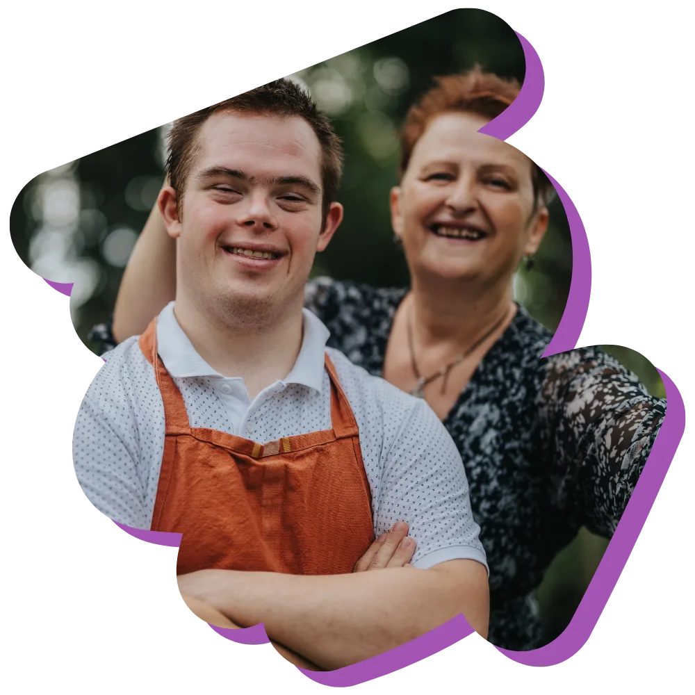 Disabled man with down syndrome smiling at camera with support worker