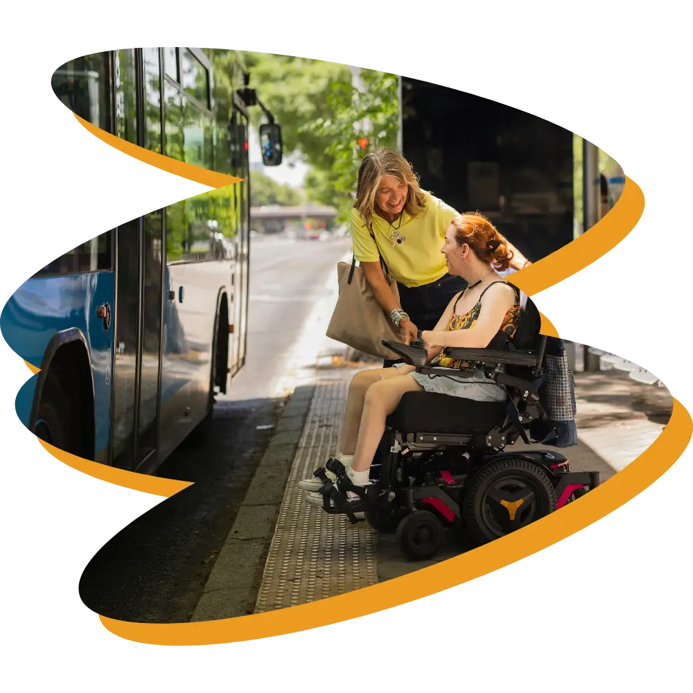 Disabled woman in wheelchair with support worker getting on bus