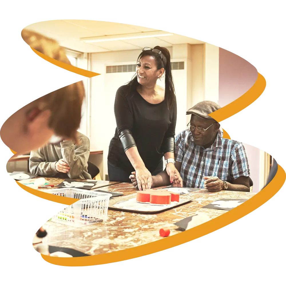 Support worker smiling and helping NDIS participants do crafts