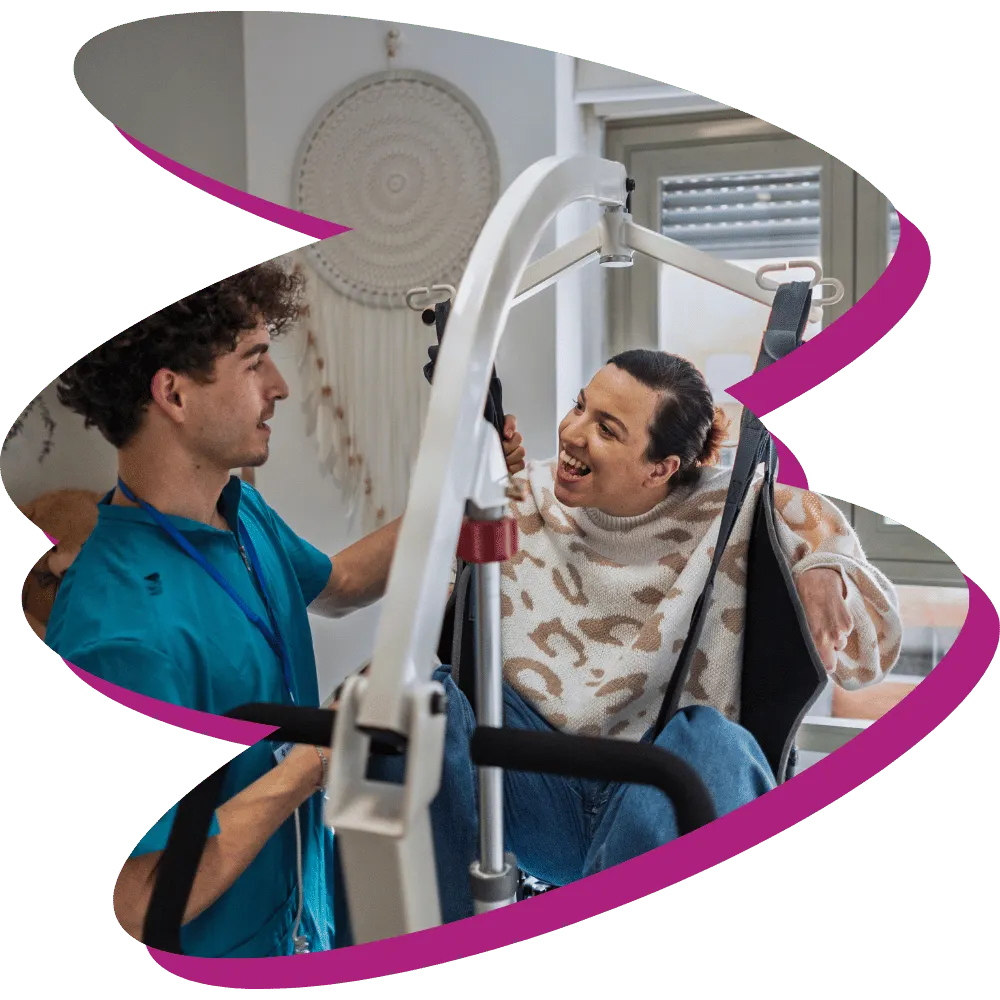 Male nurse smiling with disabled woman in hoist